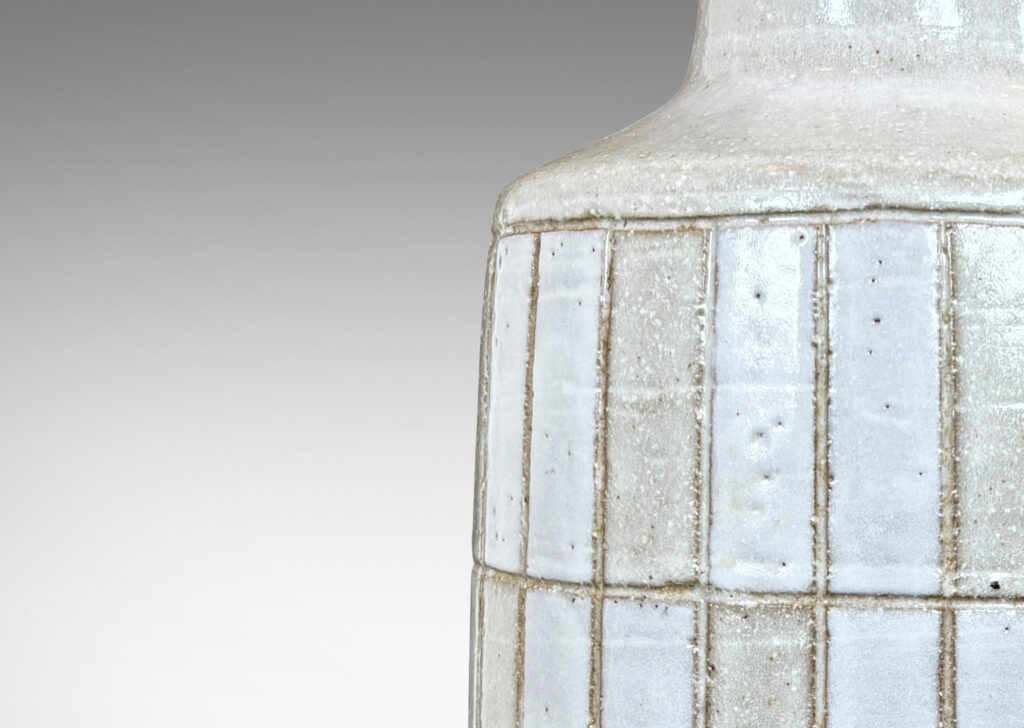 Gallery BAC cylindrical form with carved grid design, and tall conical neck, glazed in pale gray and white