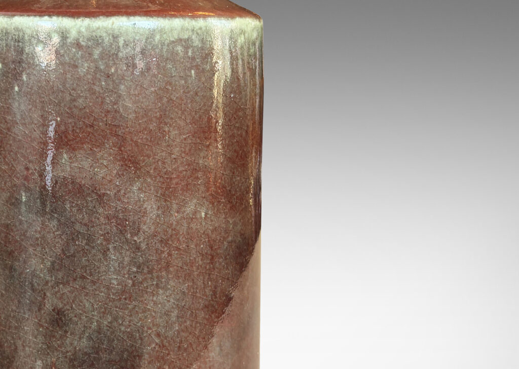 Gallery BAC cylindrical form with angled shoulders and wide mouth, glazed in a shiny oxblood burgundy-celadon green