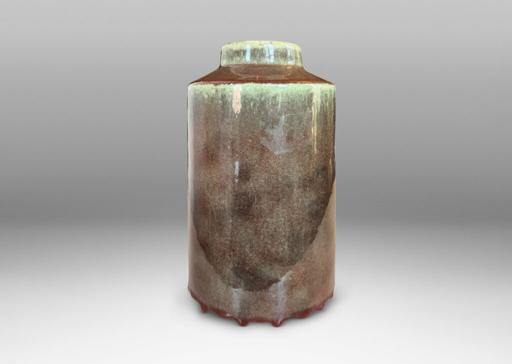 Gallery BAC cylindrical form with angled shoulders and wide mouth, glazed in a shiny oxblood burgundy-celadon green