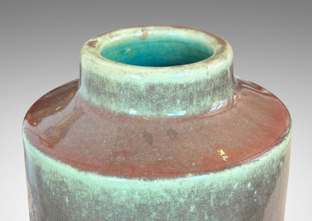 Gallery BAC cylindrical form with angled shoulders and wide mouth, glazed in a shiny oxblood burgundy-celadon green