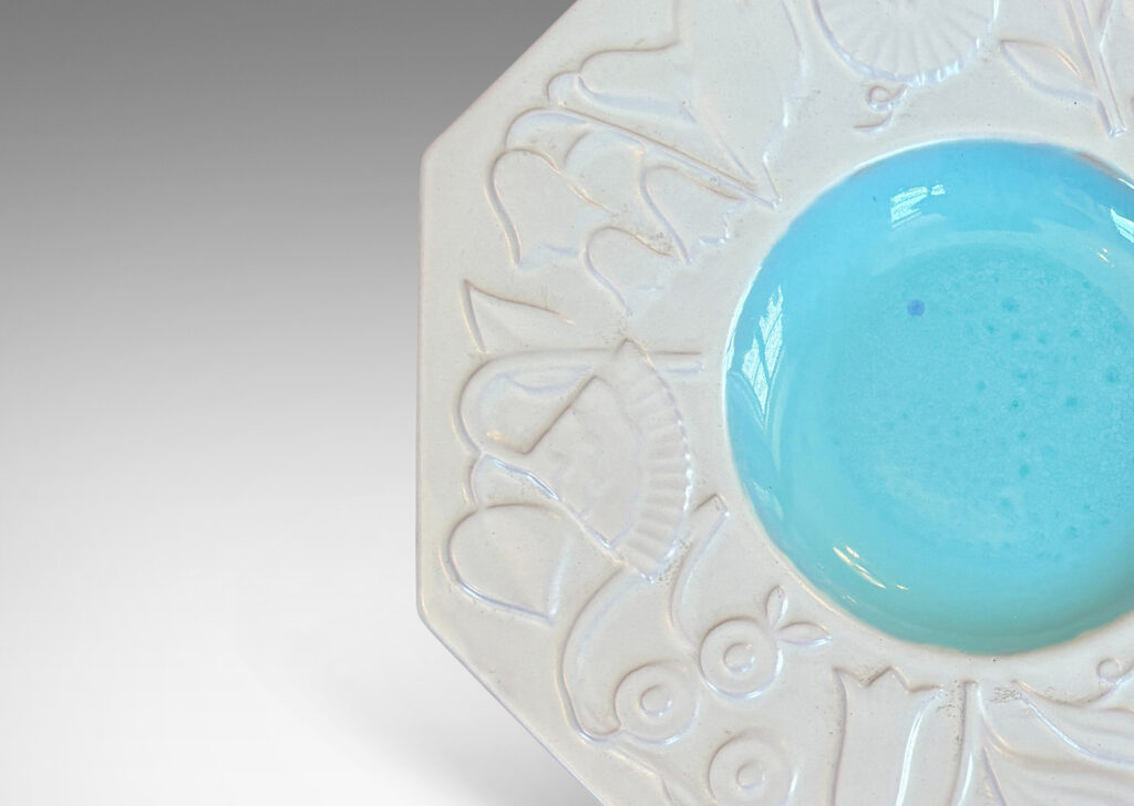 Gallery BAC shallow round center in shiny turquoise, and wide octagonal lip with stylized florals in relief glazed in eggshell finish white