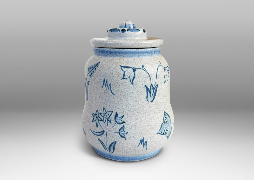 Gallery BAC undulating ovoid form with a disk lid with floral style finial, glazed in a pale gray craquel, with wildflower ornaments painted in blue