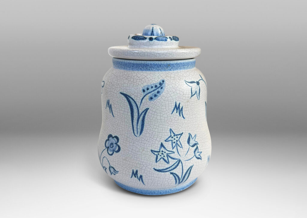 Gallery BAC undulating ovoid form with a disk lid with floral style finial, glazed in a pale gray craquel, with wildflower ornaments painted in blue