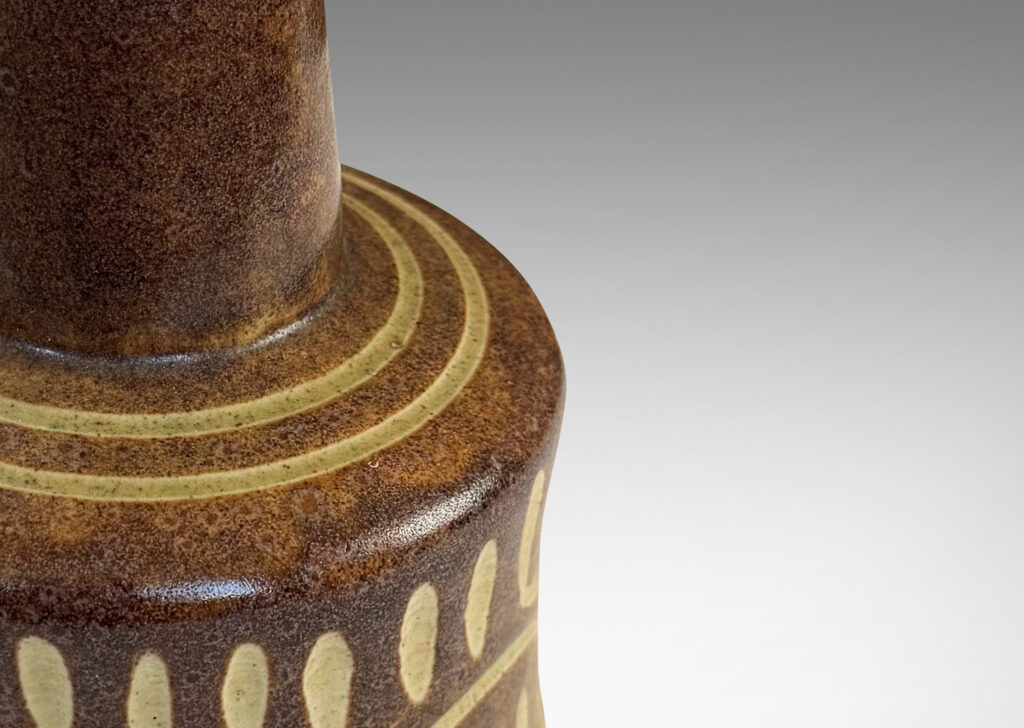 Gallery BAC drum form and conical neck, glazed in dappled brown, with carved details in ivory
