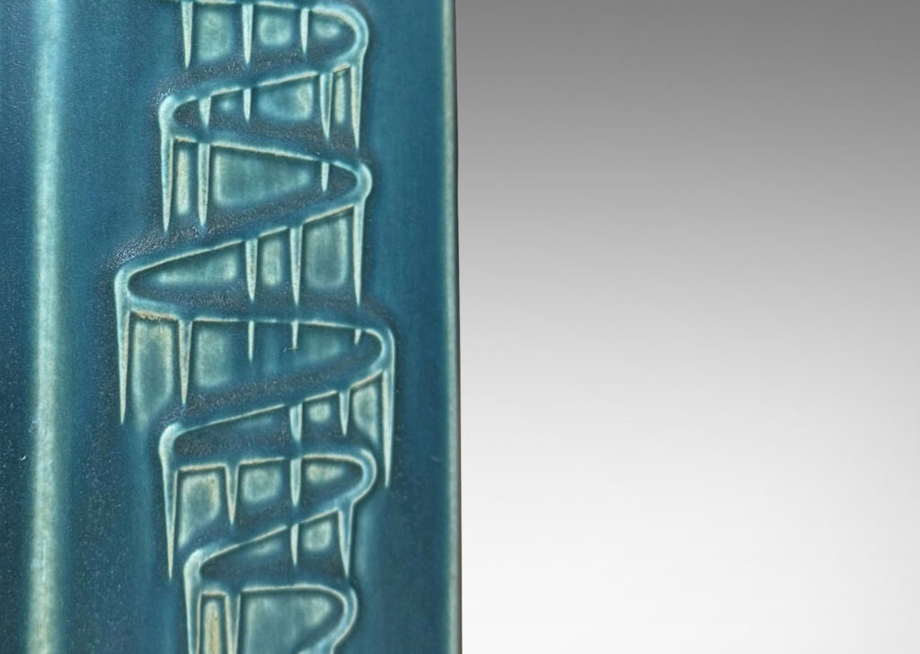 Gallery BAC square pillar forms with chamfered corners and serpentine pattern reliefs, glazed in a matte subdued turquoise