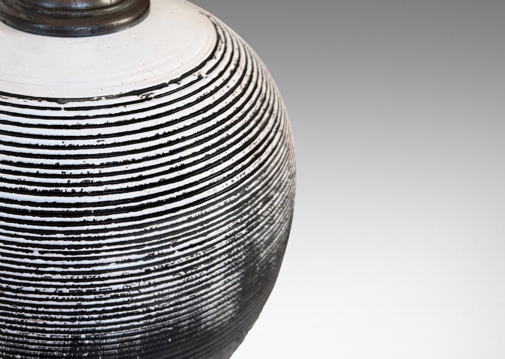Gallery BAC globe form with carved horizontal ribbing on top and rustic texture on the bottom, glazed in matte brown and shiny white