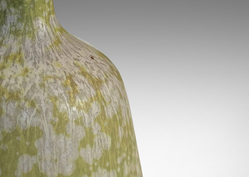 Gallery BAC angled form with delicate trumpeting neck and mouth, glazed in a dappled pale green