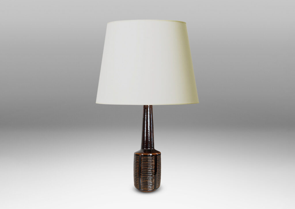 Gallery BAC cylindrical form ornamented with columns of carved lines and a tall conical neck, glazed in a shiny brown glaze