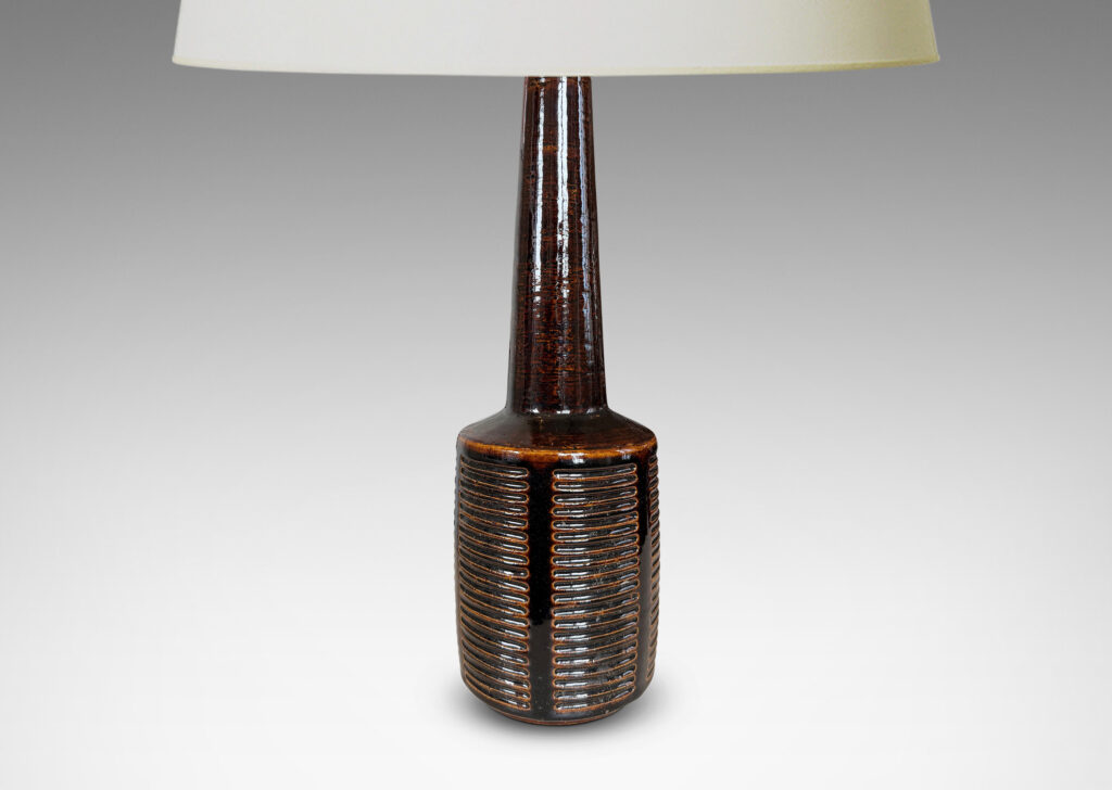 Gallery BAC cylindrical form ornamented with columns of carved lines and a tall conical neck, glazed in a shiny brown glaze