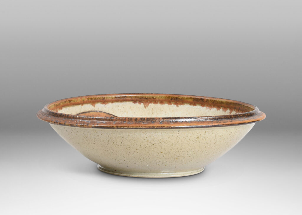 Gallery BAC articulated foot and lip, with relief abstract design inside, glazed in pale taupe and tobacco brown