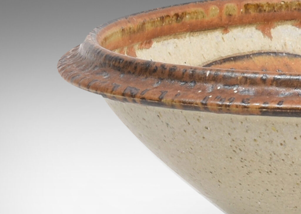 Gallery BAC articulated foot and lip, with relief abstract design inside, glazed in pale taupe and tobacco brown