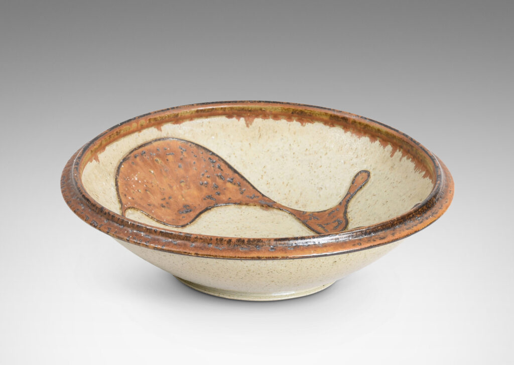 Gallery BAC articulated foot and lip, with relief abstract design inside, glazed in pale taupe and tobacco brown