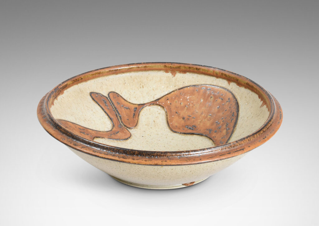 Gallery BAC articulated foot and lip, with relief abstract design inside, glazed in pale taupe and tobacco brown