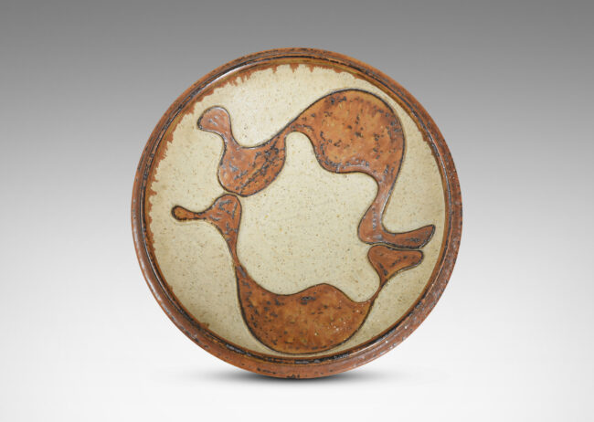 Gallery BAC articulated foot and lip, with relief abstract design inside, glazed in pale taupe and tobacco brown